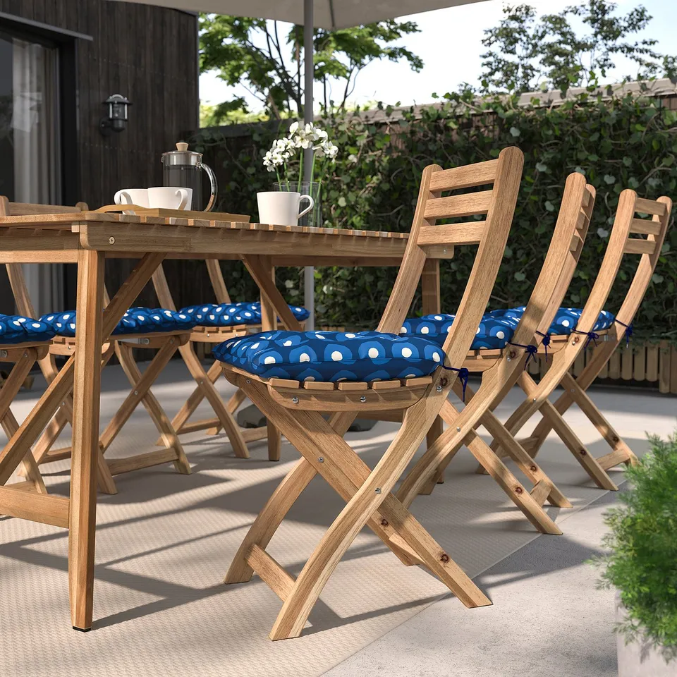 Wooden chairs with blue polka-dot cushions, coffee setup, fenced garden.
