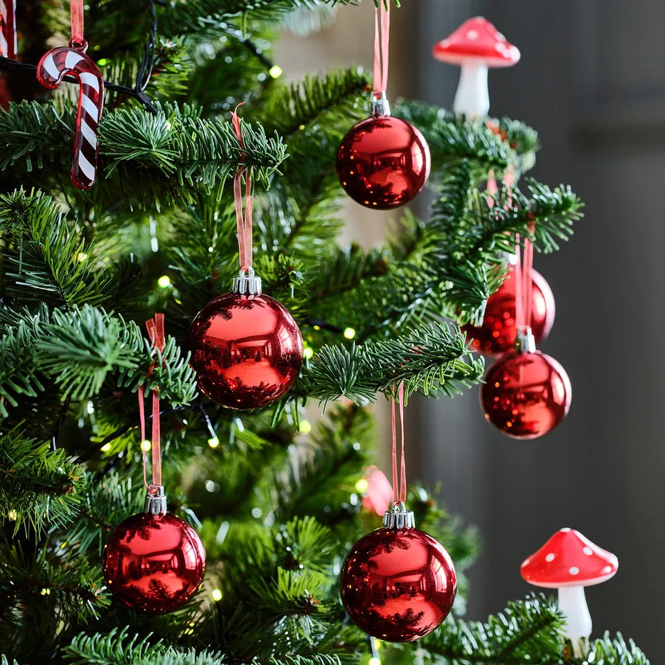 Shiny red christmas ornaments hanging on a tree, adding holiday colour and festive spirit.