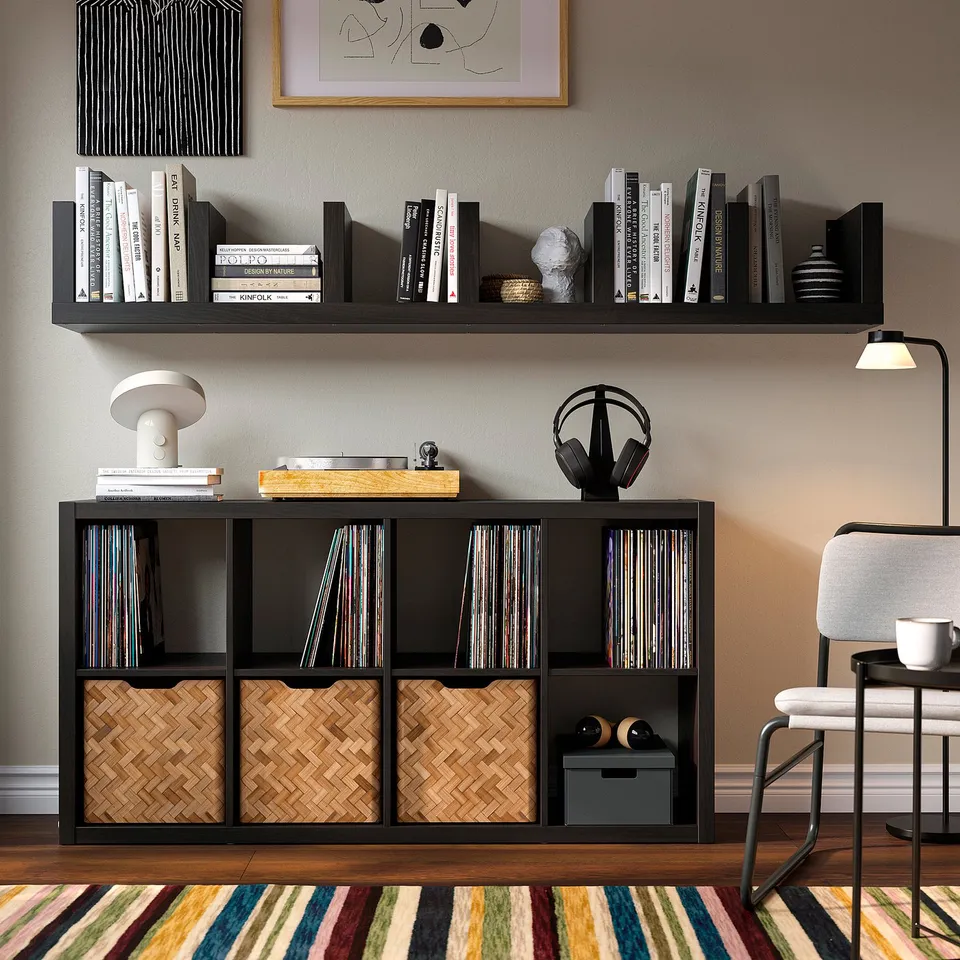 IKEA LACK wall shelf with books, vinyl, and decor. Below, matching LACK units store vinyl and baskets. Nearby chair and lamp.