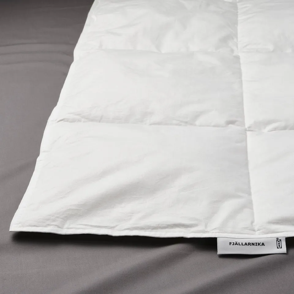 White duvet on bed, branded FJÄLLARNIKA, with fine craftsmanship.