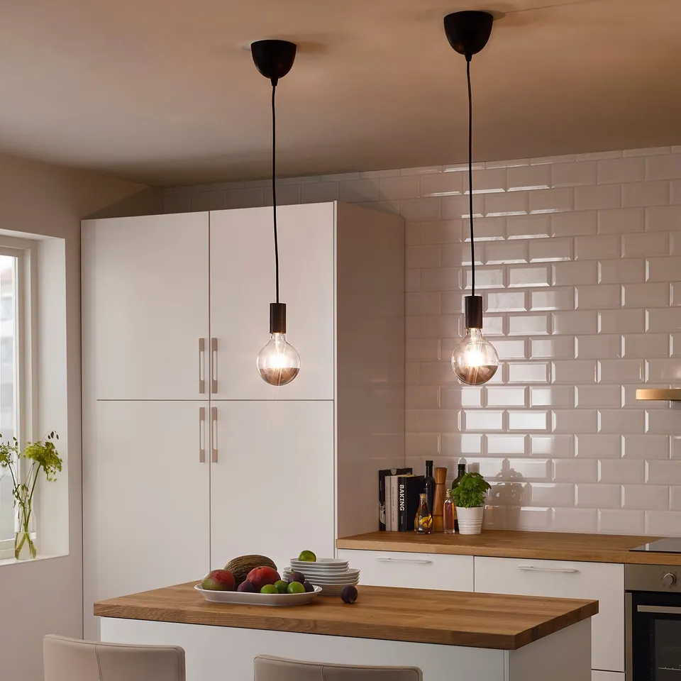 Two SUNNEBY pendant lights over kitchen island with fruit, plates, and plant.