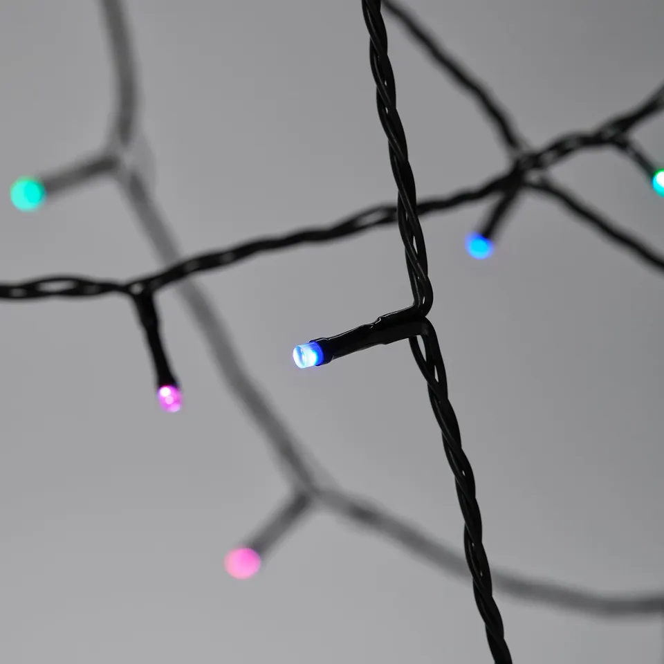 Close-up of colourful led string lights on black wires, lit in blue and pink hues, against a grey background.