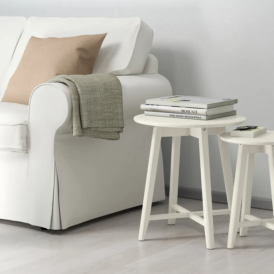 KRAGSTA side table, round, next to sofa with books.