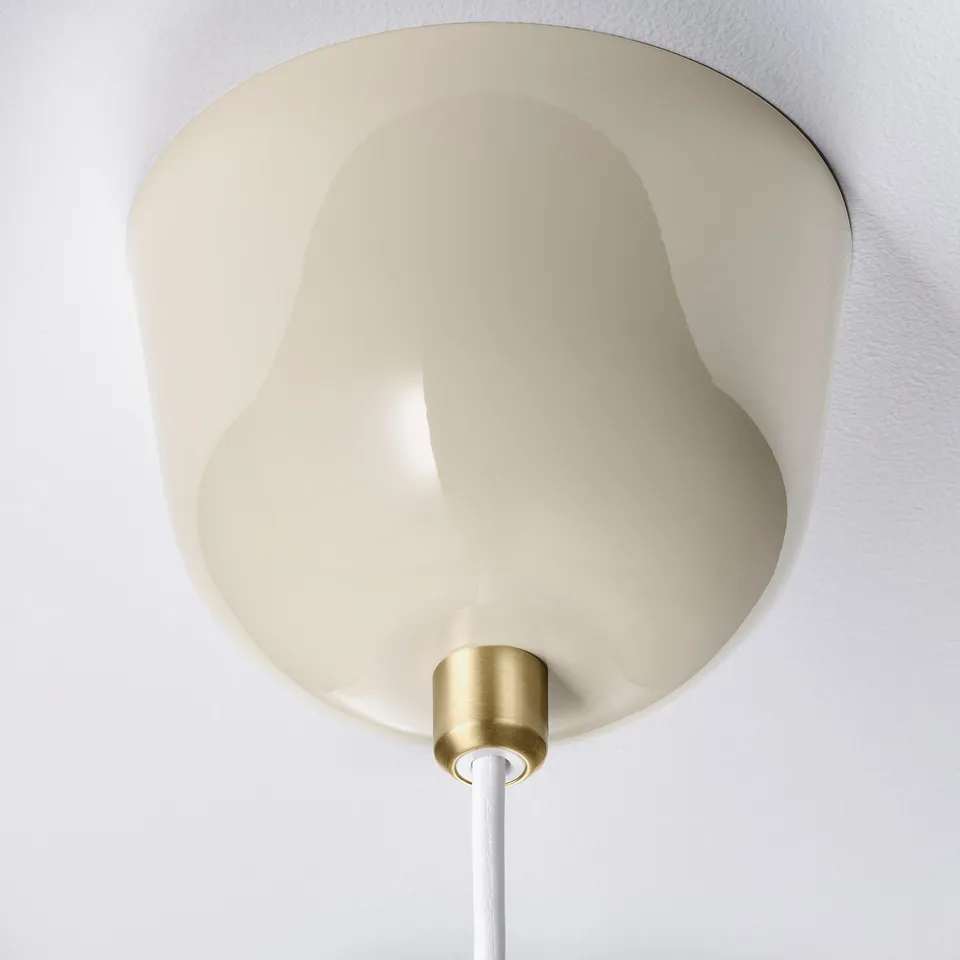 Modern pendant lamp with smooth, beige shade, gold base, and white cord.