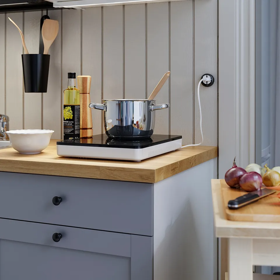 A kitchen with grey cabinets, wooden counter, and SKYDRAG light.