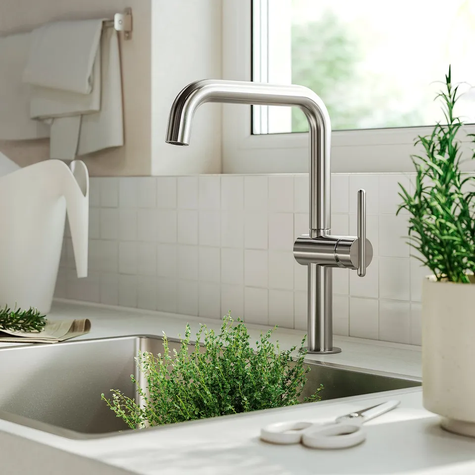 Modern kitchen with MÖRKASJÖN chrome tap, stainless steel, sleek design, placed near green herbs, scissors, and white sink.