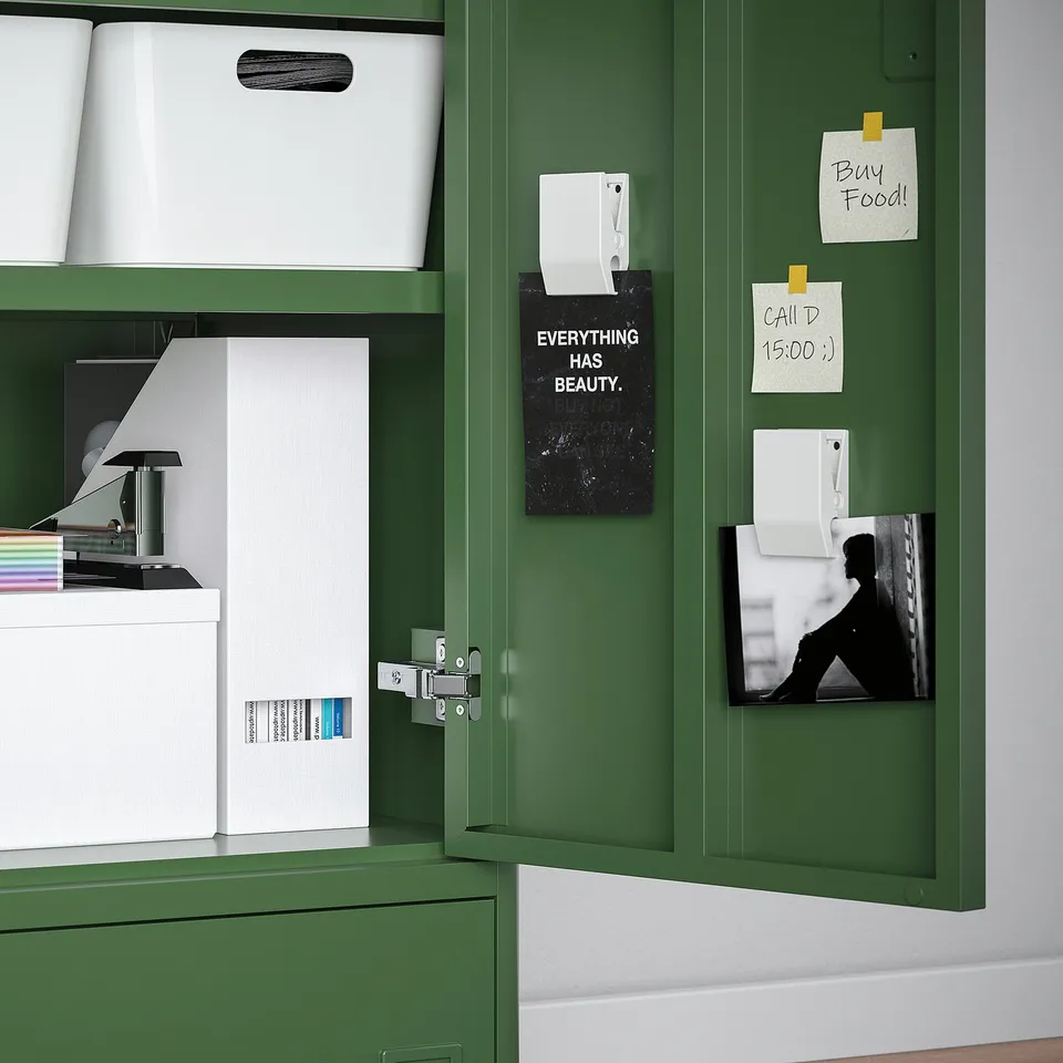 Green filing cabinet with open drawer showing white boxes and printer. Magnets hold notes and photo.