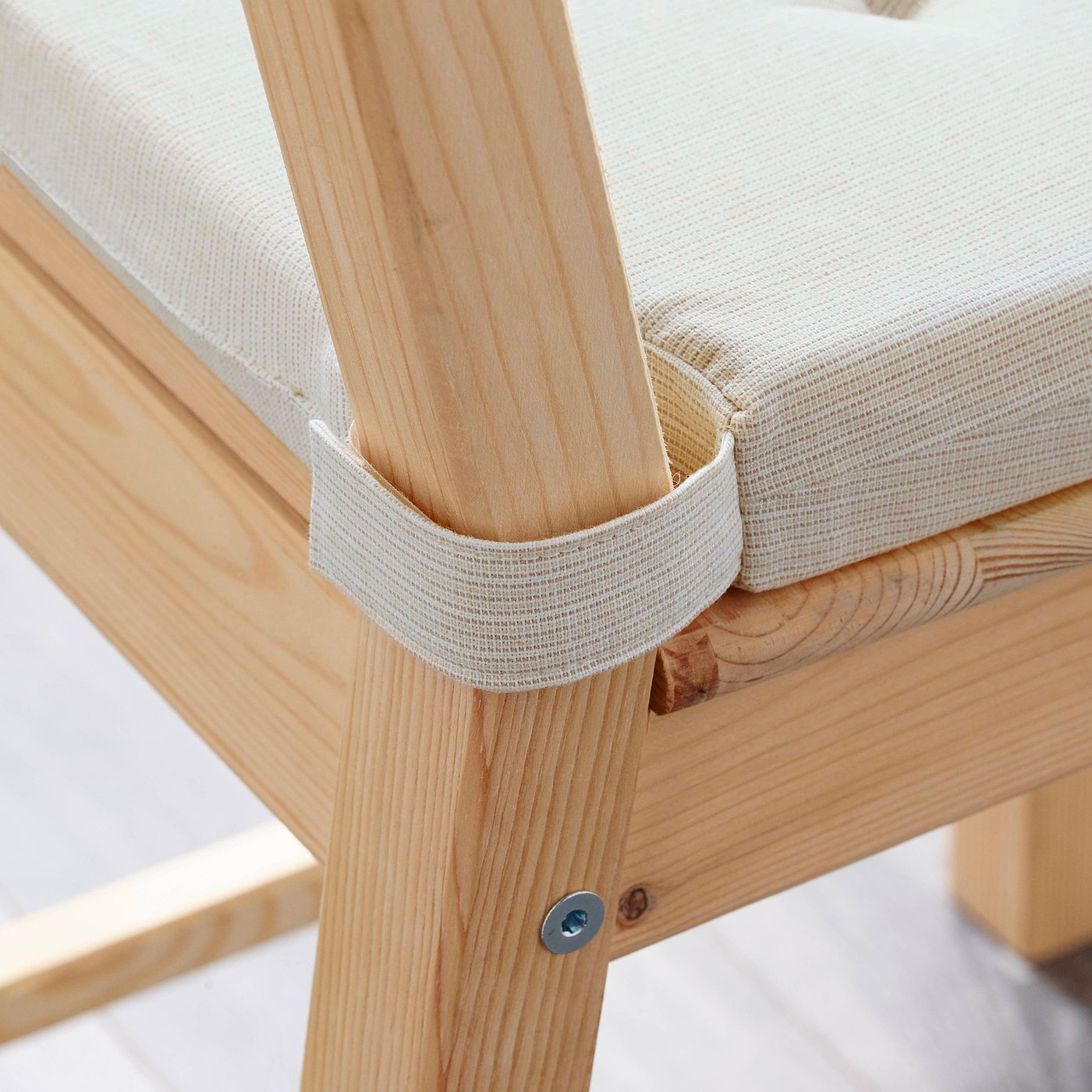 A chair pad with soft foam for comfort, attached to a wooden chair with loops for secure placement.