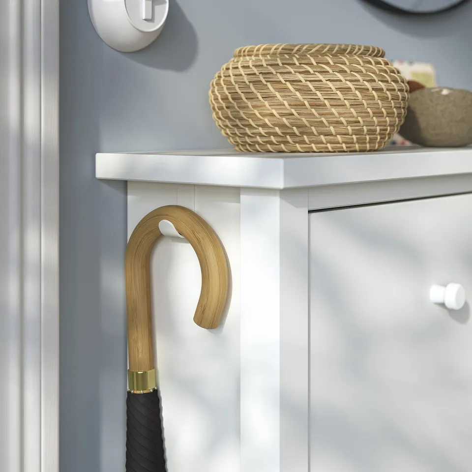 White GULLABERG shoe cabinet with woven basket and wooden umbrella hook. Modern, functional design.