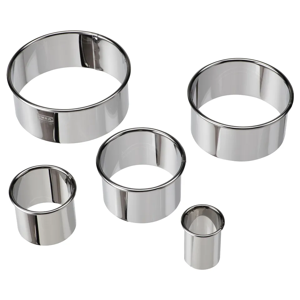 Five shiny silver metal cookie cutters in various sizes and shapes, arranged together.