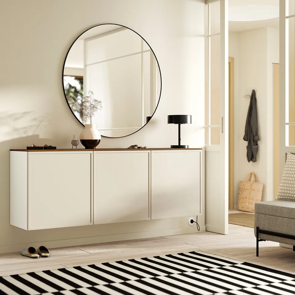 Modern entryway with BESTÅ sideboard, mirror, lamp, and vase on wooden top. Black & white rug, shoes beside, clean aesthetic.