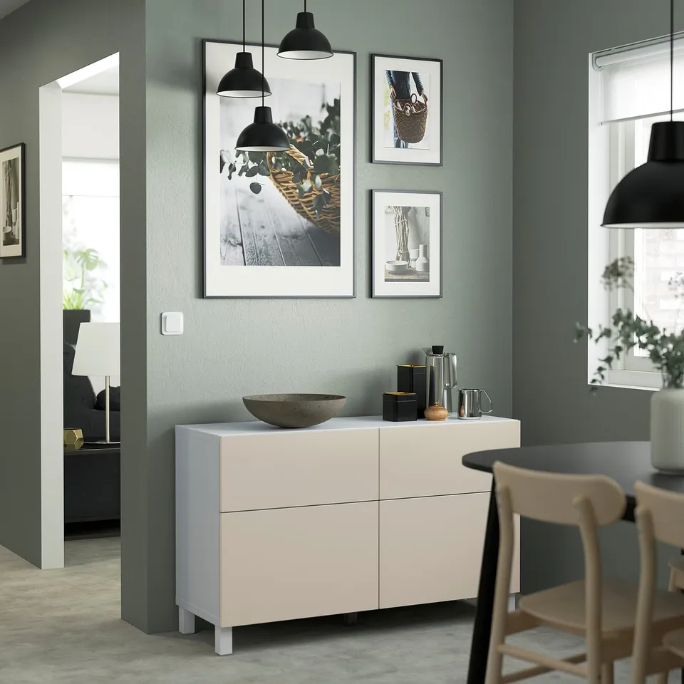 Modern sideboard with decor, flanked by chairs and a lamp, in a minimalist room.