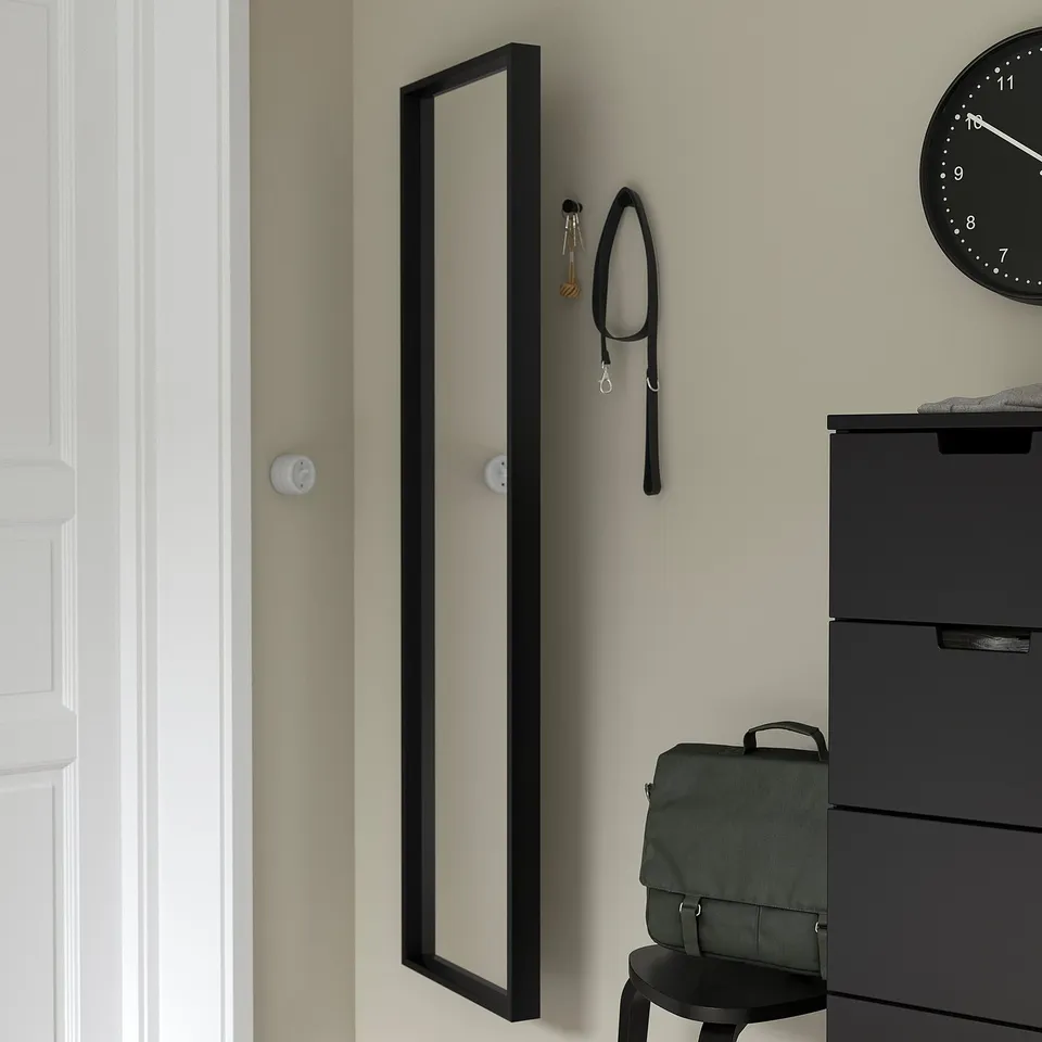 Mirror with keys and lanyard hooks, reflecting clock.