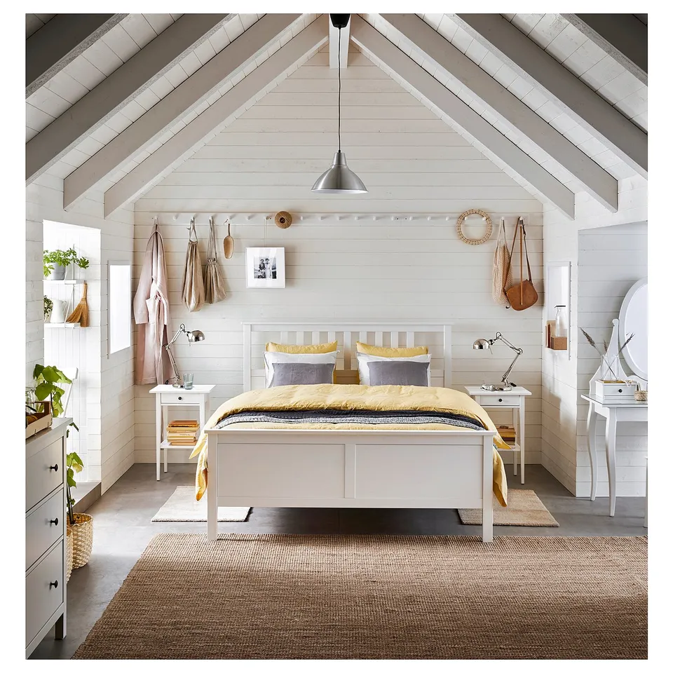 Bright, minimalist bedroom with white pine HEMNES bed, yellow bedding, hanging bags, plants, and simple decor.