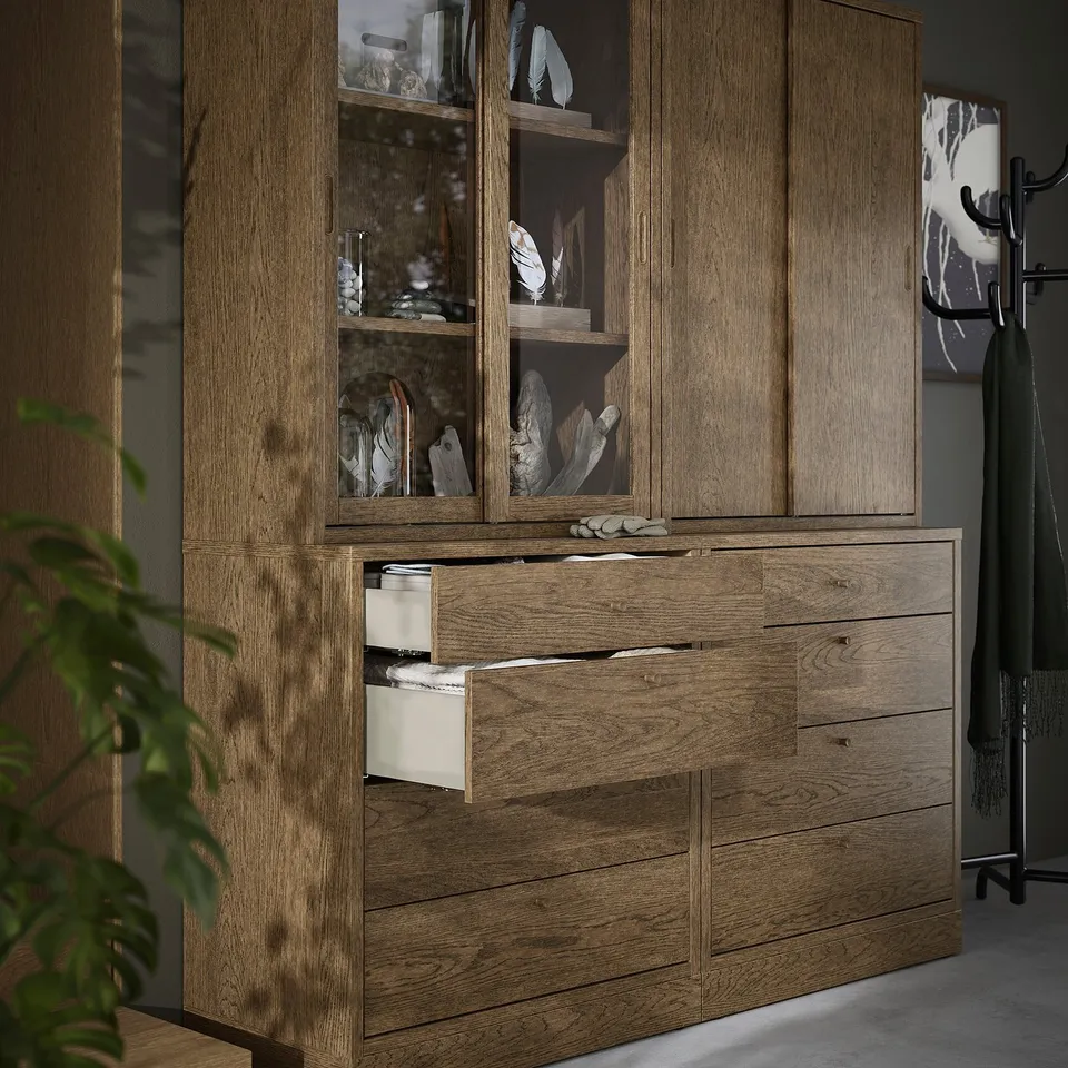 Brown wooden cabinet with sliding glass doors and drawers, showcasing decorative items.