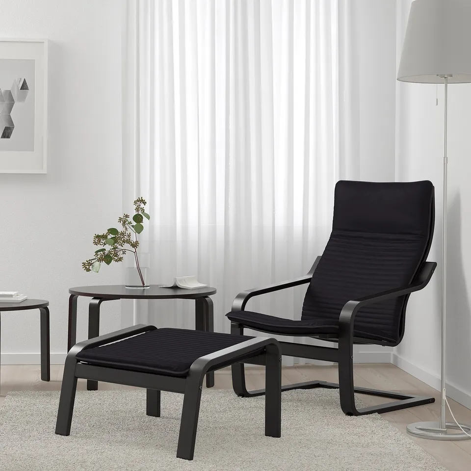 Modern living room with black POÄNG recliner, high back, white curtains, lamp, and plant.