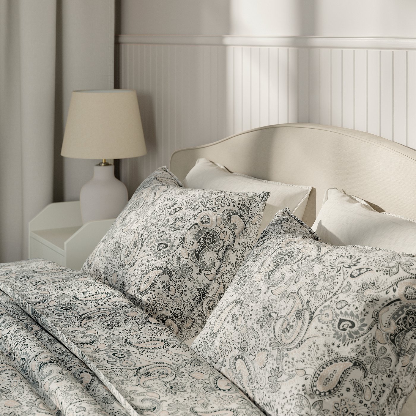 Bed with removable, washable cover and padded headboard. Lamp on bedside table; serene bedroom setup.