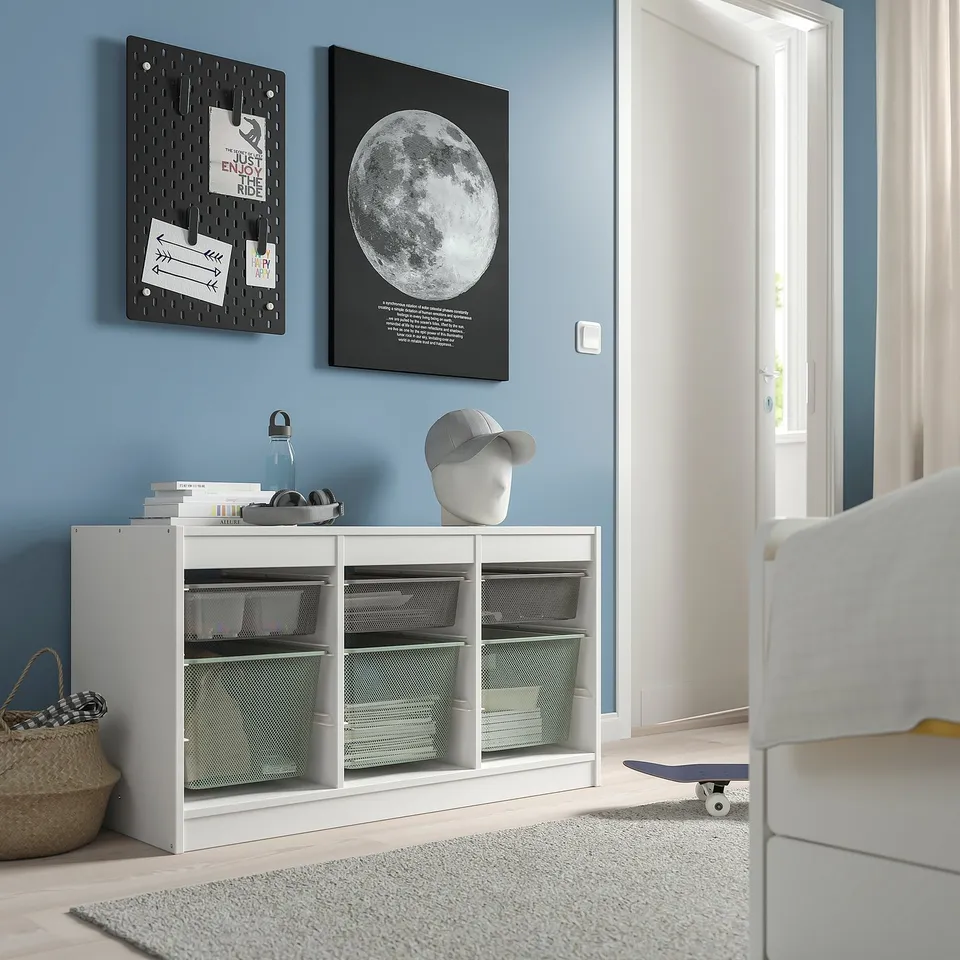 White PJÄTTERYD storage unit against blue wall, moon picture, notes, mannequin with cap, skateboard.