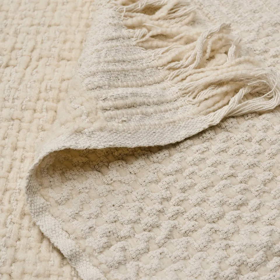 Handwoven cream throw with textured weave, soft and cosy, showcasing natural fibres.