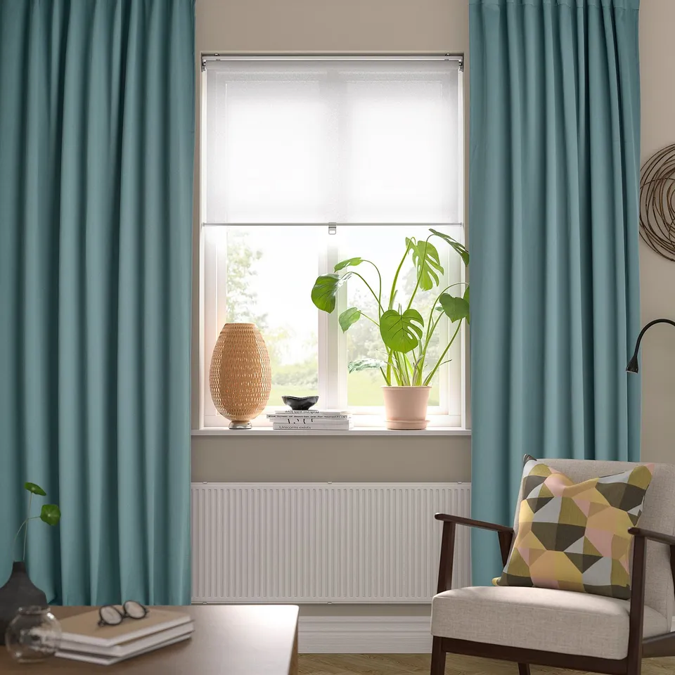 Living room with MAJGULL dark curtains, plant-filled window, colourful chair.