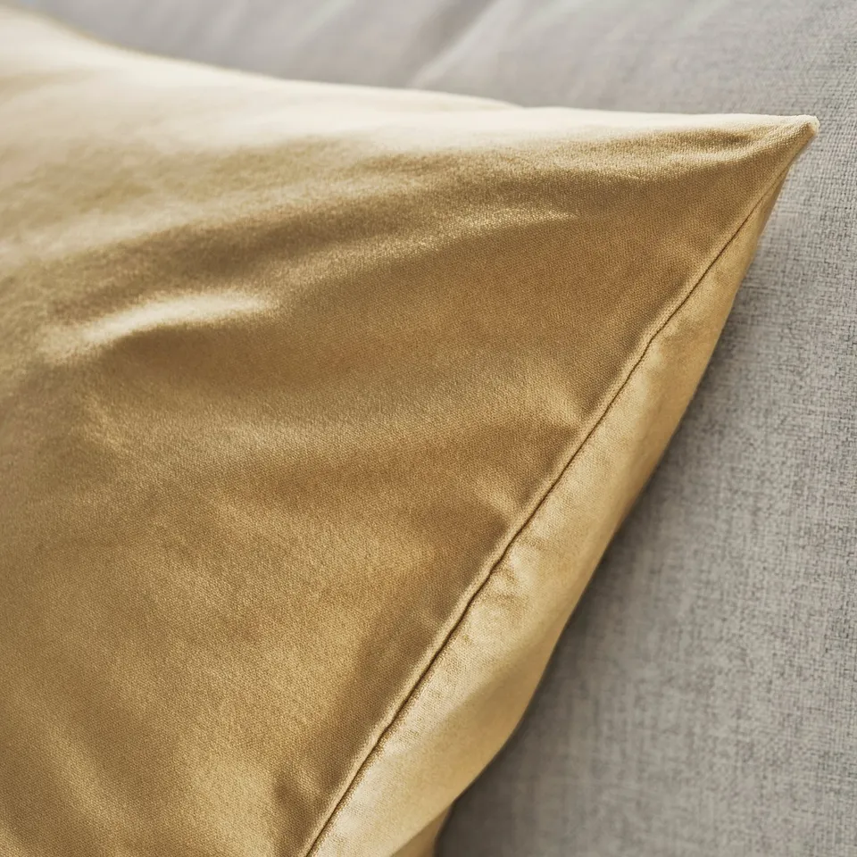 Gold-colored velvet cushion cover with a smooth, luxurious texture and subtle sheen.