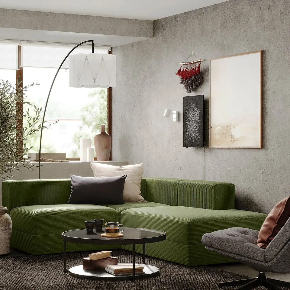 Modern living room with green JÄTTEBO modular sofa, grey rug, industrial-style lamp, abstract art, and plants.