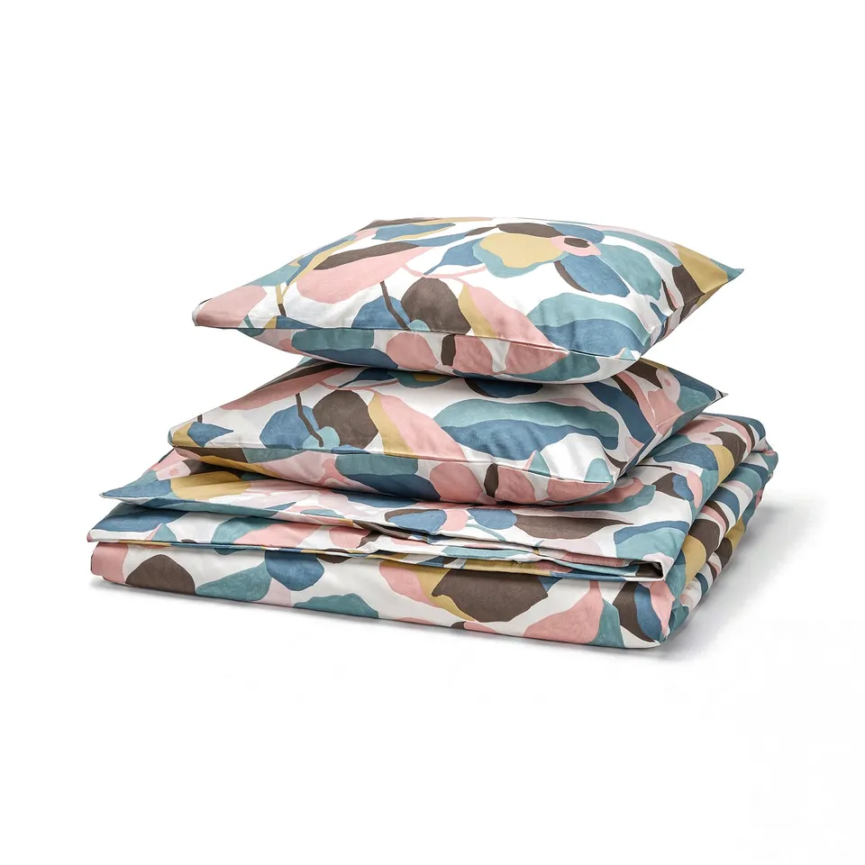 Folded multicoloured leaf-patterned bedding set featuring warm earthy tones, with a mix of cotton and lyocell material.