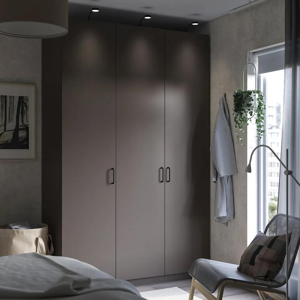 Minimalist bedroom with grey wardrobe, hanging chair, plant, and bed.