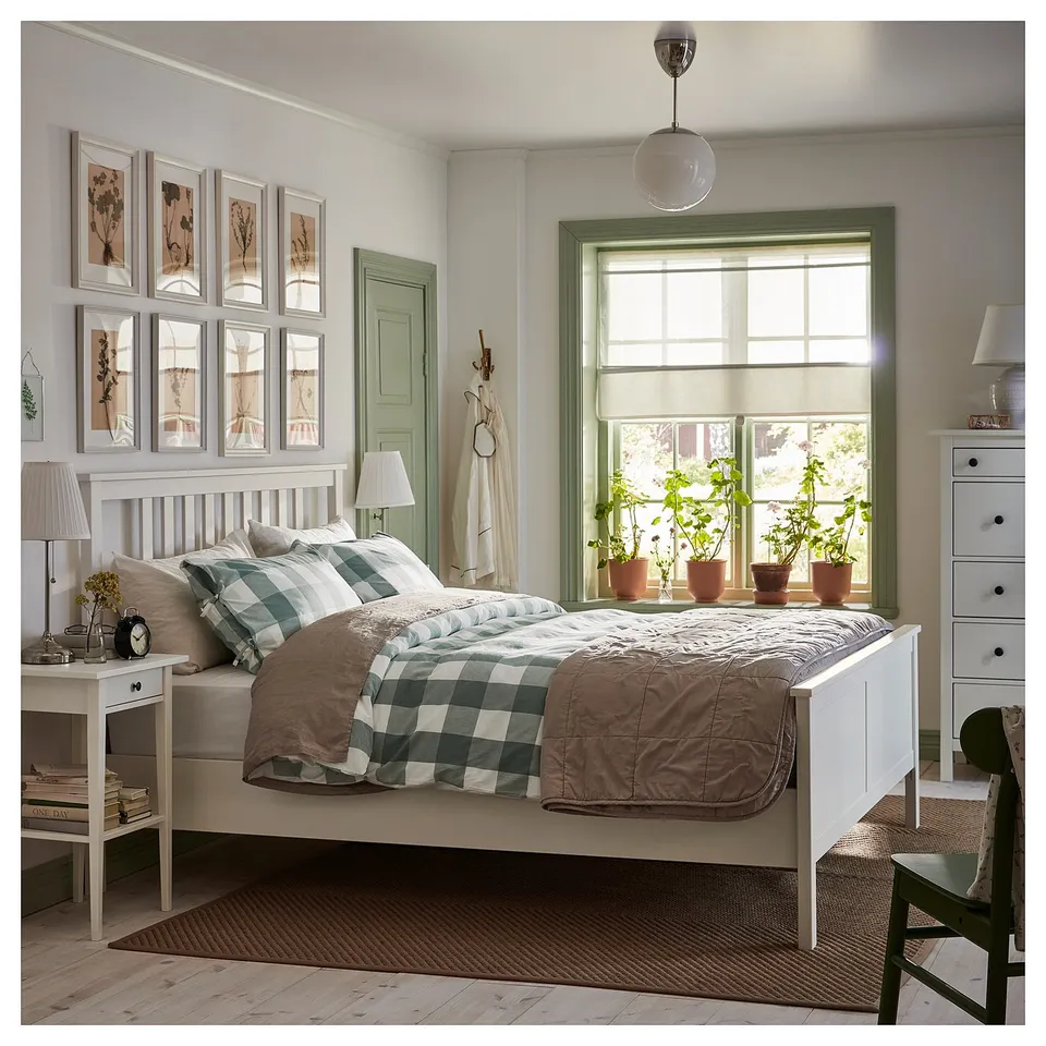 Bright bedroom with white HEMNES wood bed, green trim window, plants, green chair, and white dresser.