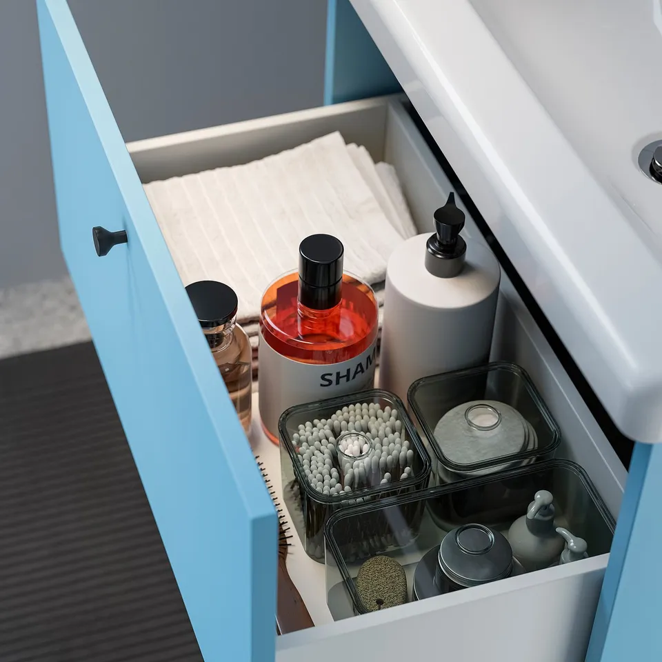 A blue bathroom vanity with drawers open, showing toiletries and organised containers.