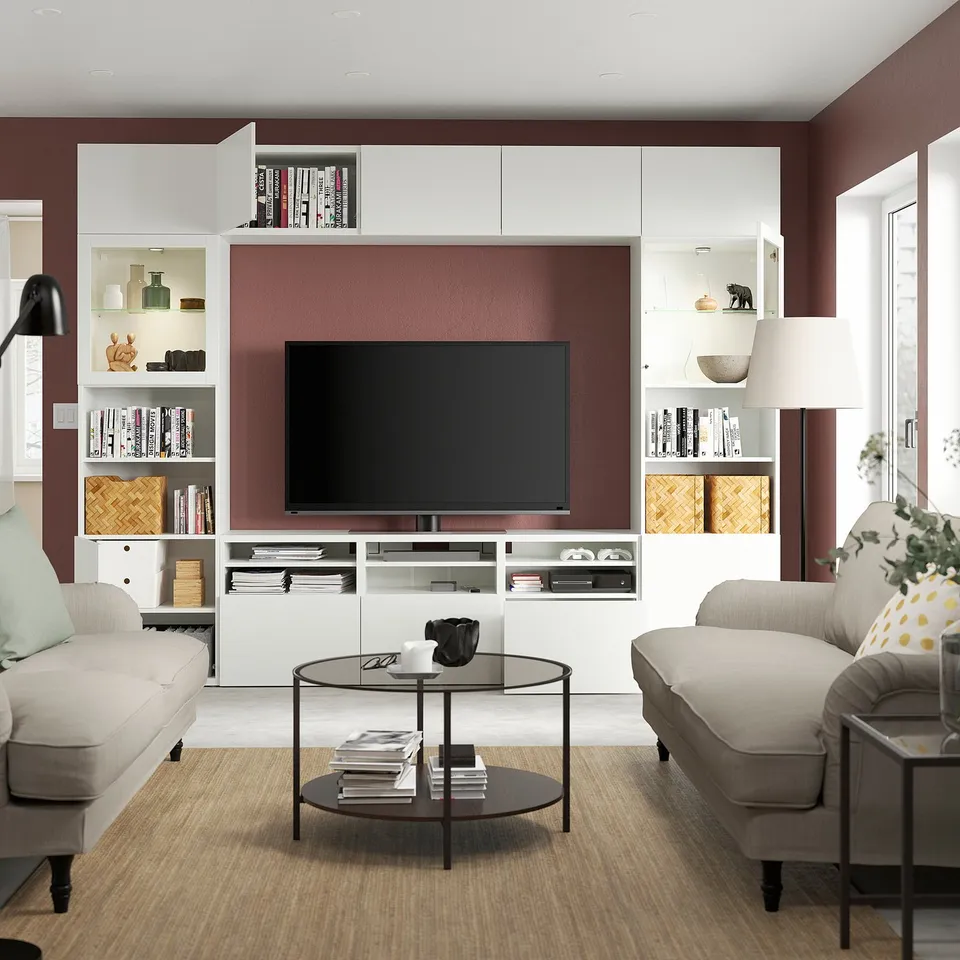 Modern living room with BESTÅ tv unit, displaying a tv, books, and decor. Adjustable shelves, cable management, and wall-mounted cabinets.