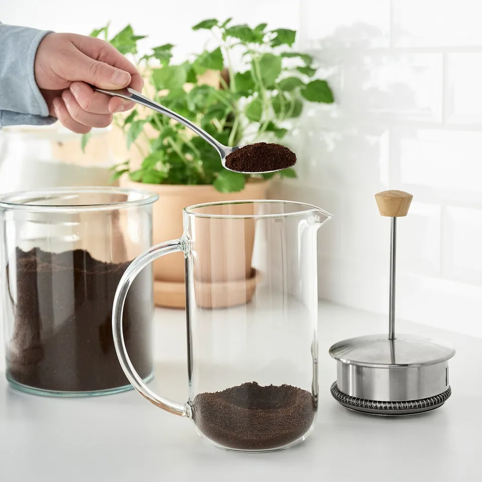Adding coffee grounds to glass maker on counter