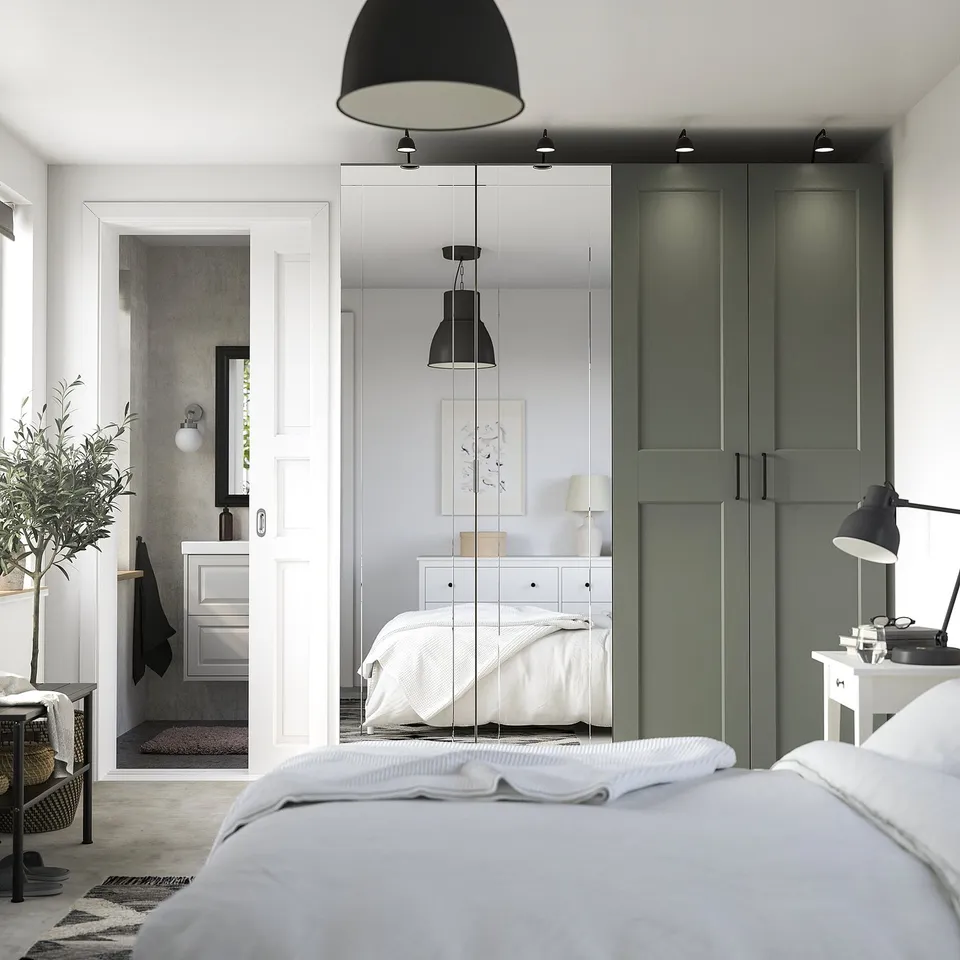 Modern bedroom with tall green PAX wardrobes, mirrored doors, and storage.