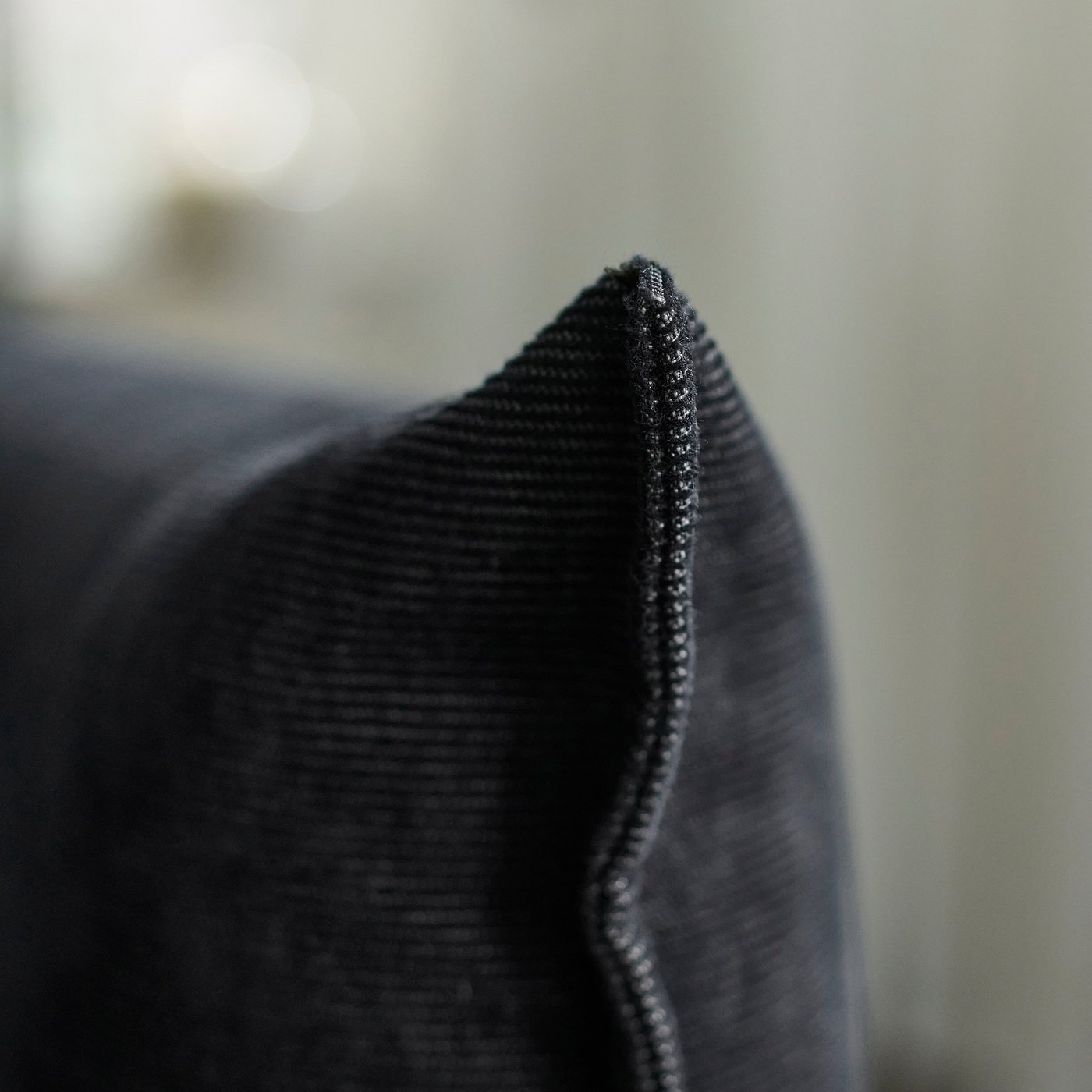 Close-up of durable, textured black fabric sofa with intricate stitching detail, showcasing quality craftsmanship.