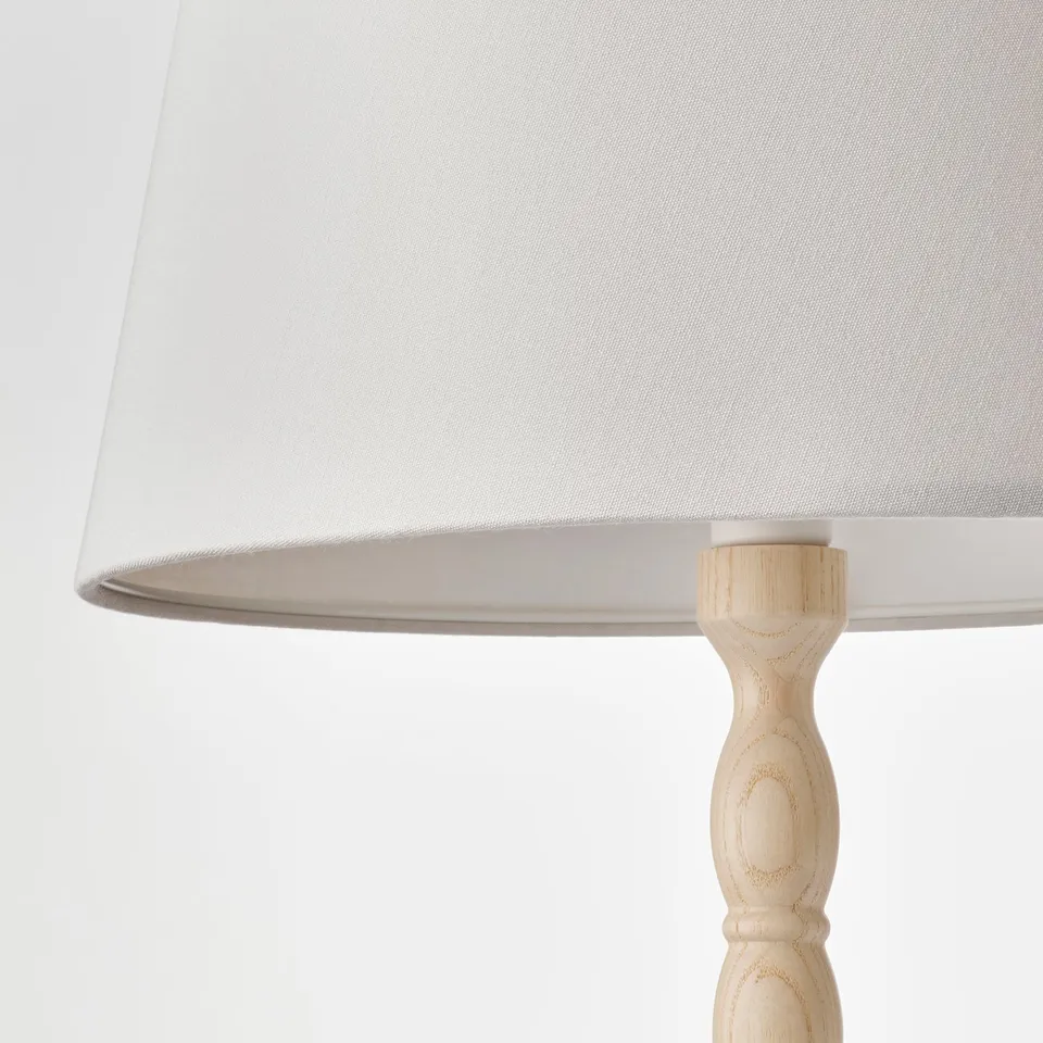 White lampshade on intricately turned wooden base.