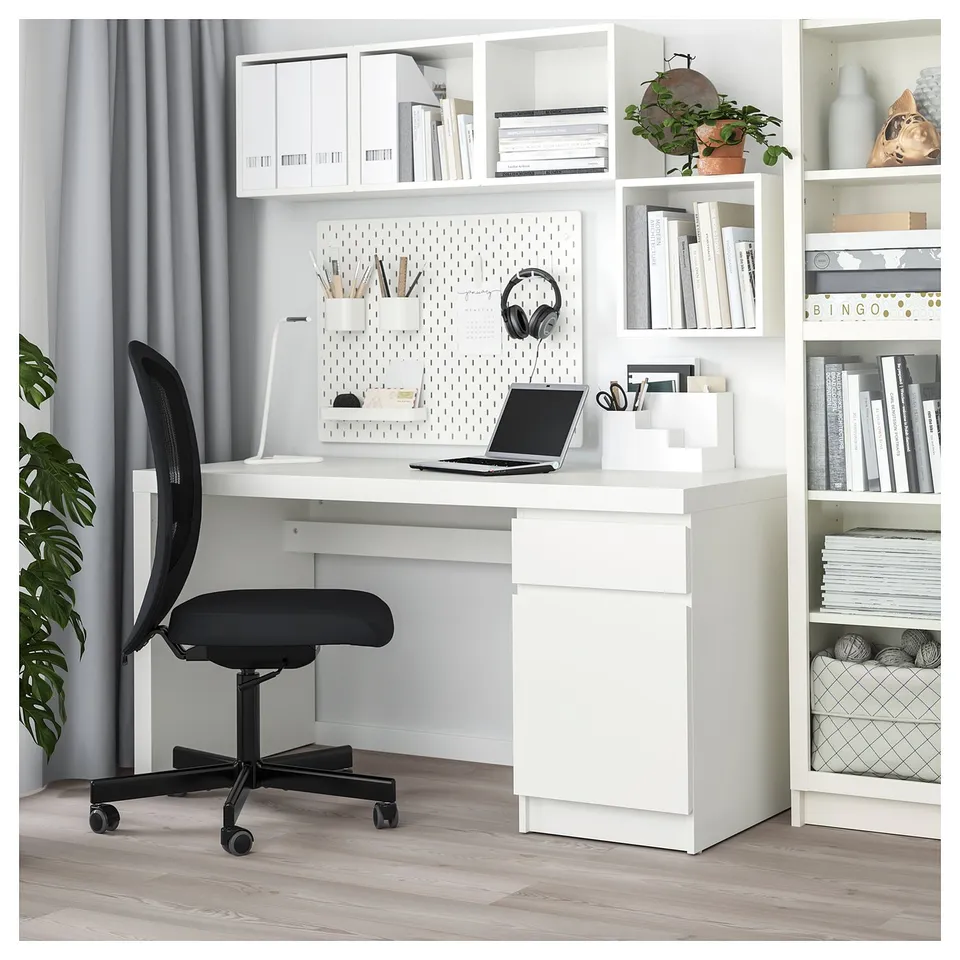 Well-organized home office with white MALM desk, black chair, and shelves holding books, decor, and office supplies.