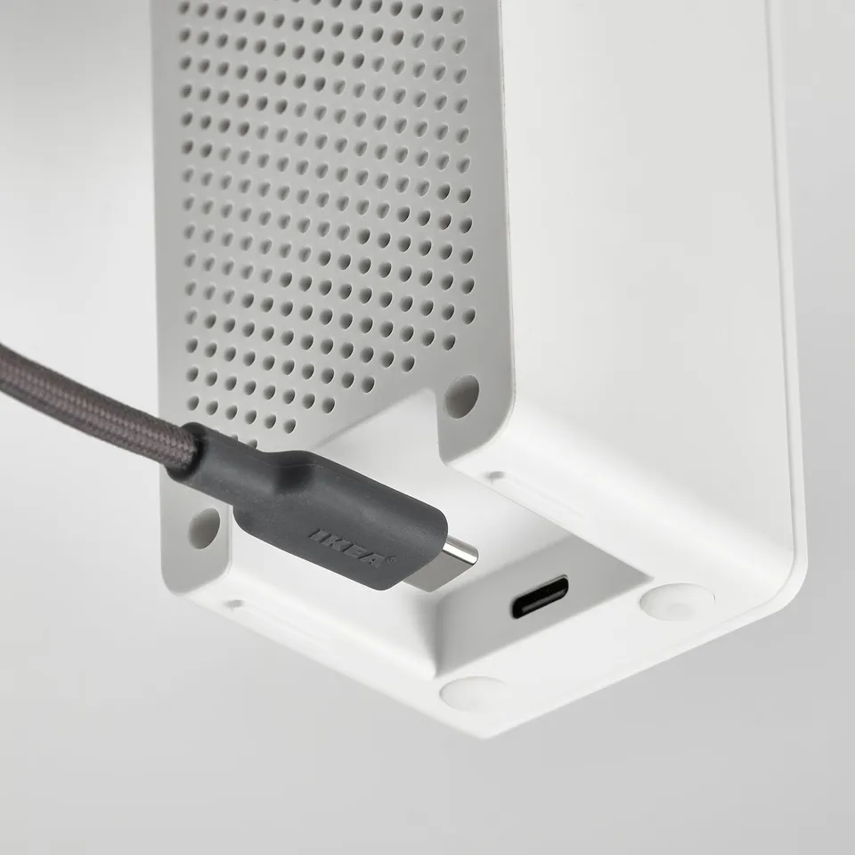 A white air quality sensor with a usb-c port where a power cord is connected, indicating its powered on.