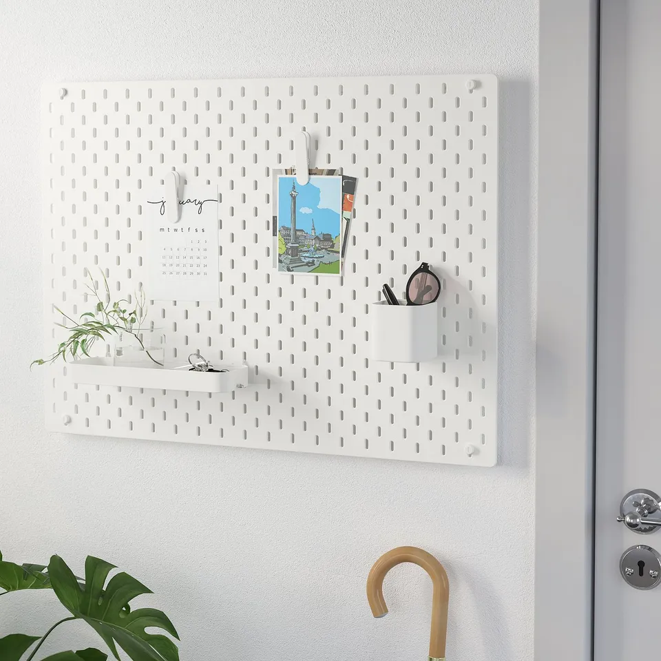 White wall organiser with hooks, cups, and calendar.