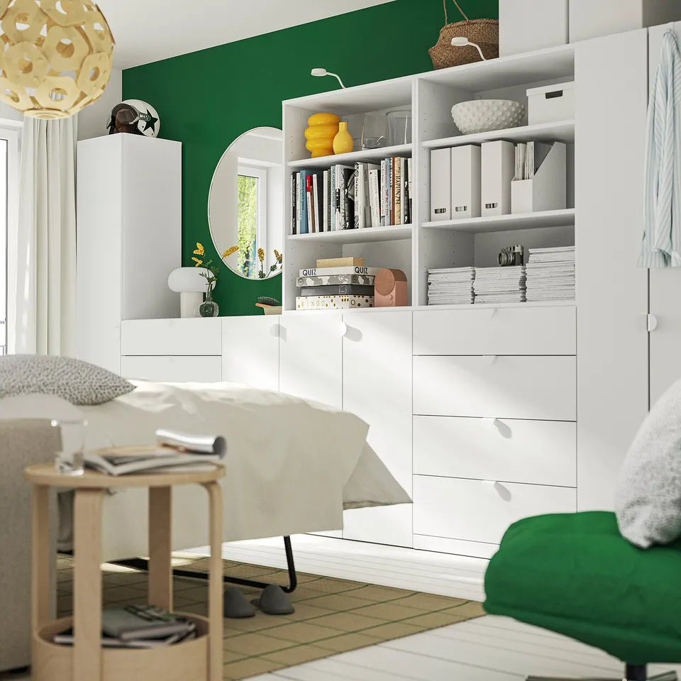 Room with green wall, large storage unit, bed, and decor.