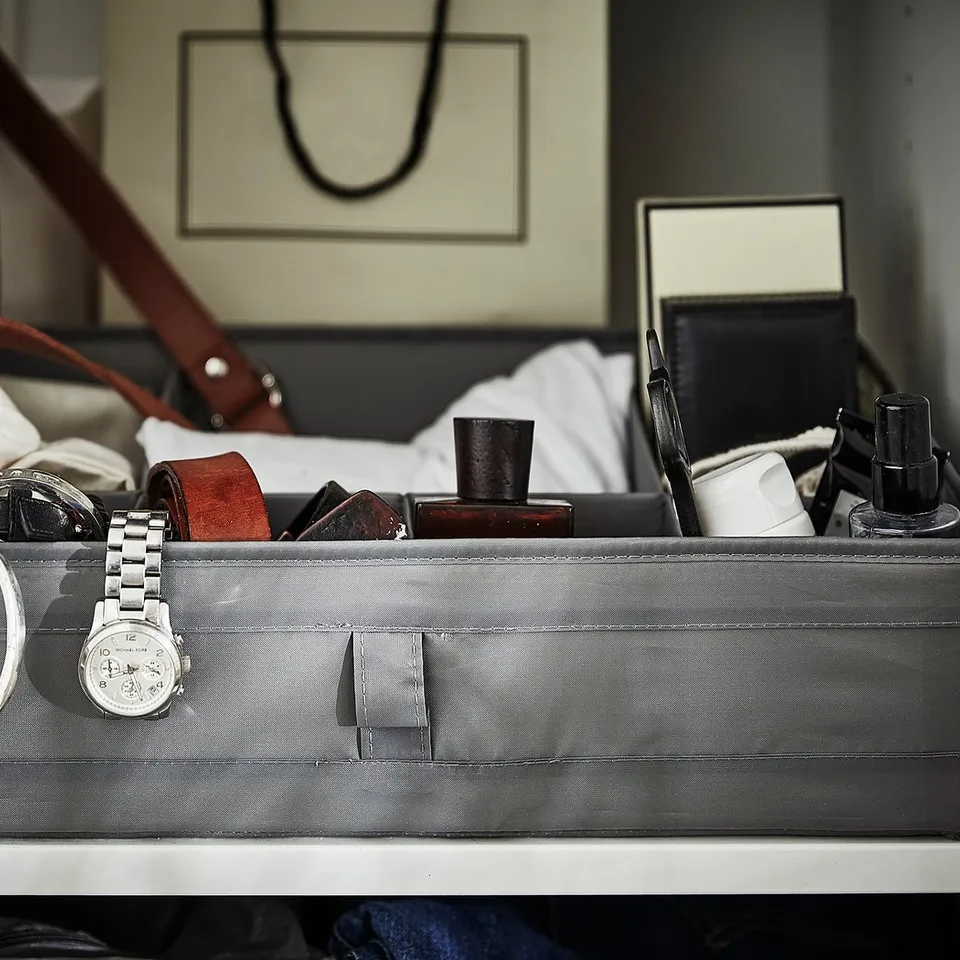 Grey SKUBB organiser box with watch, bracelets, and small items on a shelf.