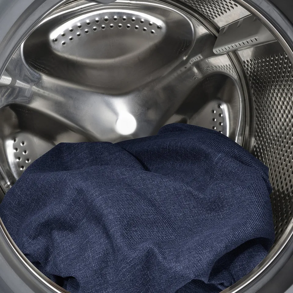 Washing machine drum with dark clothing item inside.