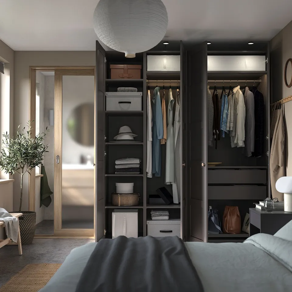 Bedroom with black PAX wardrobes, clothes, bed, lamp.