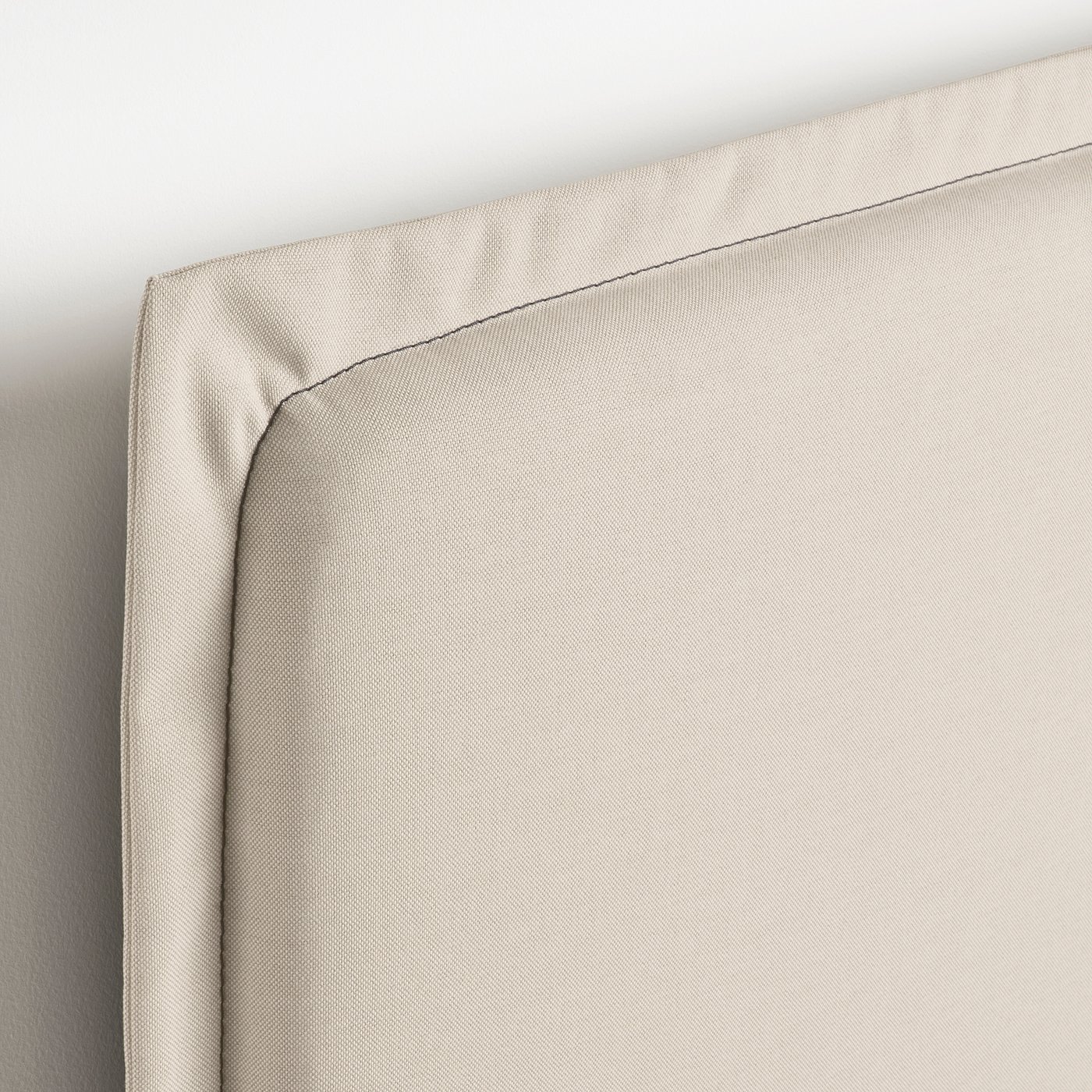 Close-up of a well-crafted, upholstered bed frame corner, showing soft, clean fabric and neat stitching.