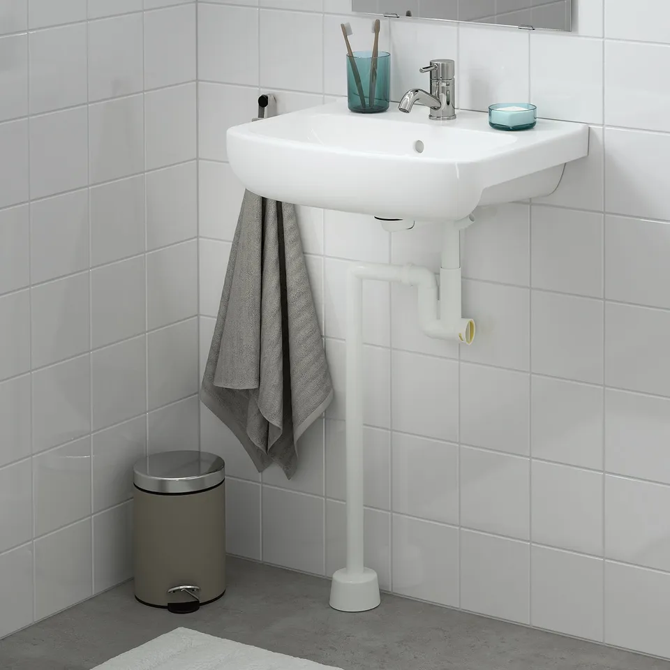 White bjorkan sink, tiled wall, single bowl. Grey towel, silver rubbish, blue cup.