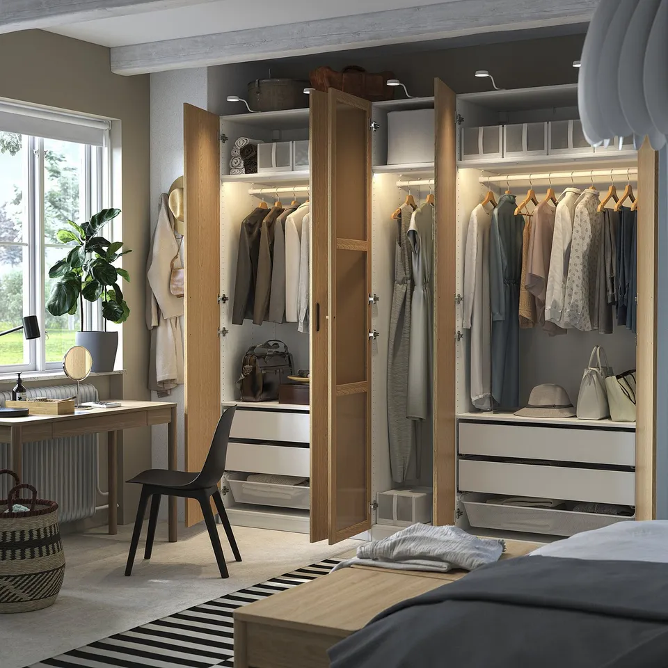 A well-lit wardrobe organiser with clothes, accessories, and drawers, featuring built-in lights and adjustable shelves.