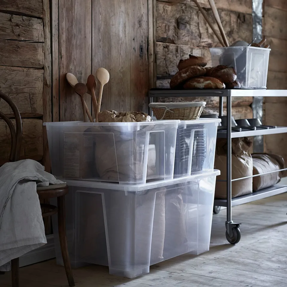 Clear plastic storage boxes on wheels in a rustic room with wooden walls and tools.