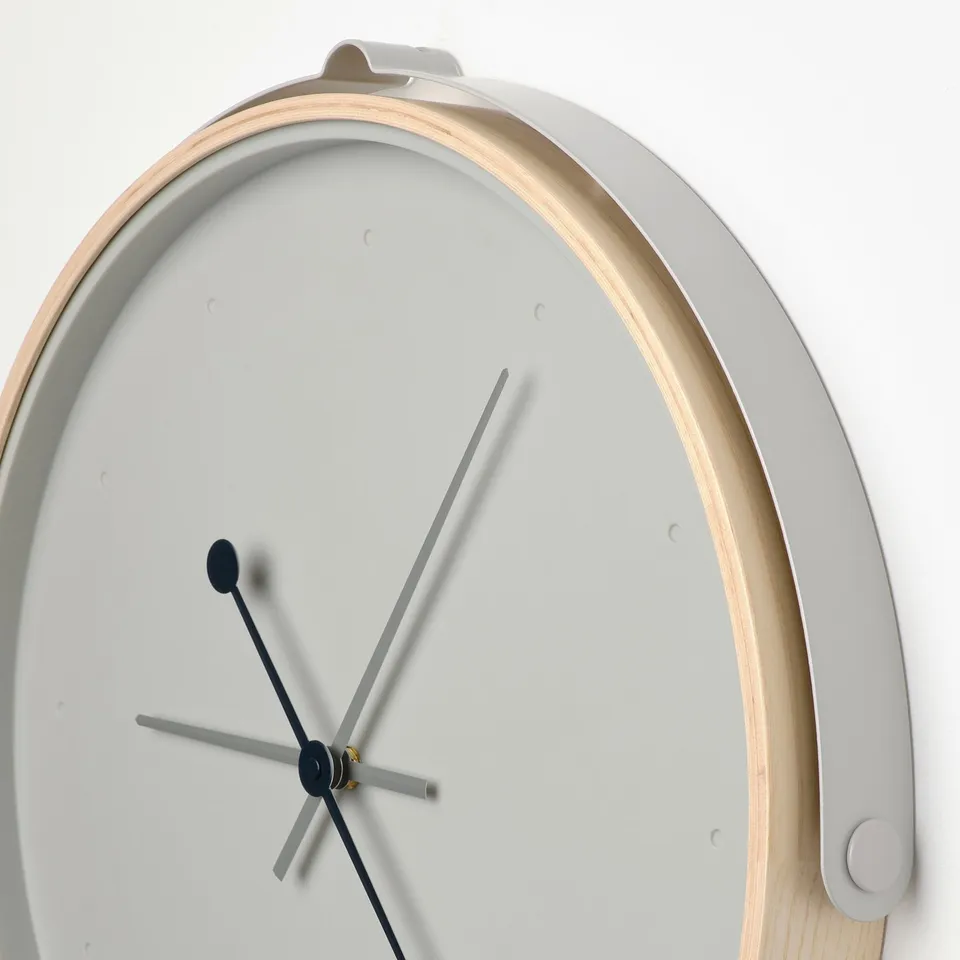 Minimalist round silent clock with black hands on bright face, wooden frame.
