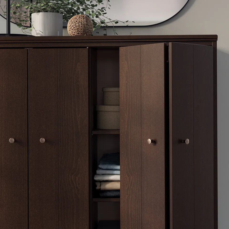 Dark wooden cabinet with open doors revealing folded clothes, topped with decorative items.