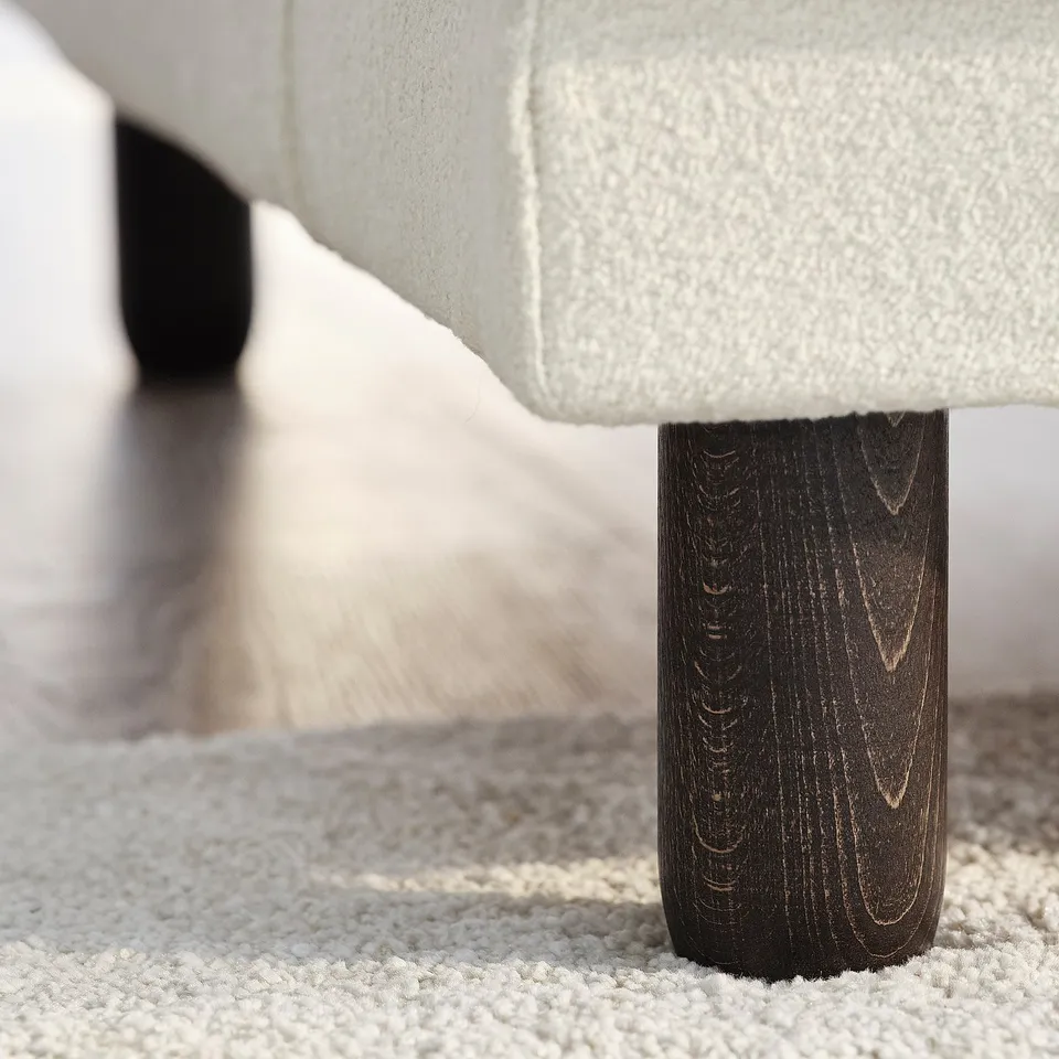 Close-up: UPPÅKRA sofa leg on soft rug. Dark wood, clean lines, durable design.