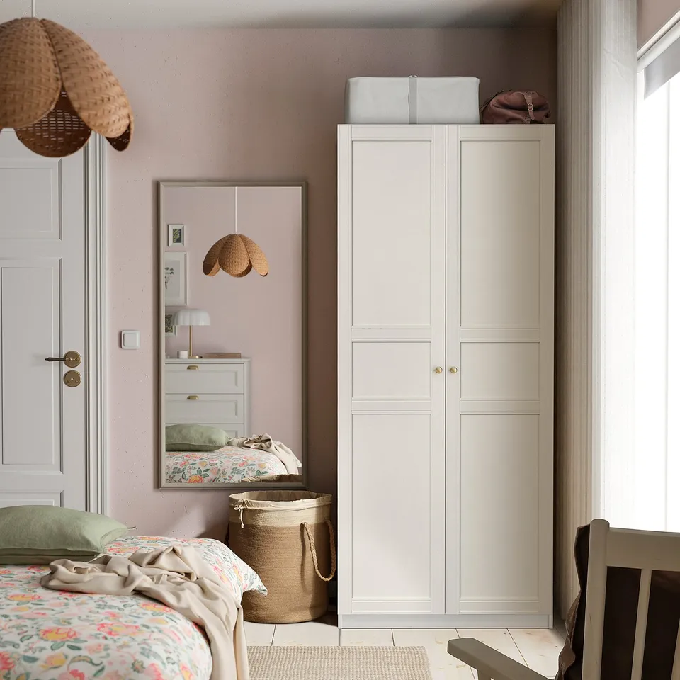 Cosy bedroom with white PAX wardrobe, floral bedding, hanging wicker basket, and beige rug.